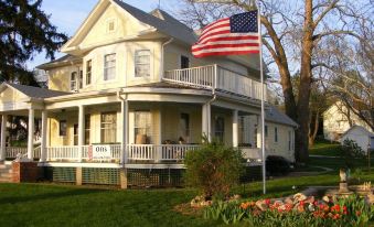 a large white house with a flag flying in front of it , surrounded by a grassy yard at Oft's Bed and Breakfast