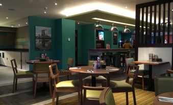 a dining area with several tables and chairs , some of which are occupied by people at Premier Inn Oban