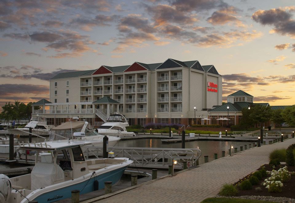 a large hotel situated on the edge of a body of water , with boats docked nearby at Hilton Garden Inn Kent Island