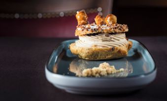 a plate with a pastry topped with cream and caramel , sitting on a dining table at Hotel Christiania