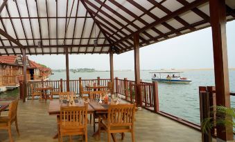 a wooden dining table with chairs is set up on a deck overlooking the water at Poovar Island Resort