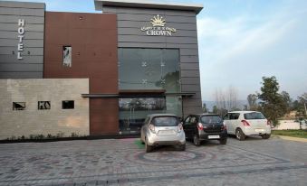 "a large building with a sign that says "" crown grand "" has two cars parked in front of it" at The Crown