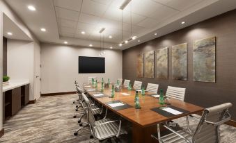 a conference room with a large wooden table , white chairs , and a tv mounted on the wall at DoubleTree by Hilton Hartford - Bradley Airport
