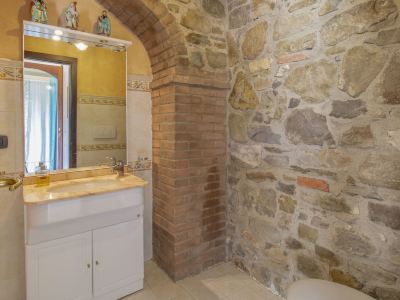 a bathroom with a white sink and a stone wall , featuring a mirror above it at Messi