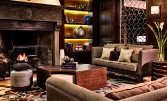 a cozy living room with a large fireplace , comfortable couches , and a rug on the floor at Renaissance Tuscany Il Ciocco Resort & Spa