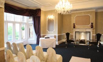 a well - decorated room with white drapes , a chandelier , and a dining table set for a formal event at Burnley West Higher Trapp Hotel