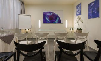 a conference room with a white table , black chairs , and a large painting on the wall at Avenue Boutique Hotel