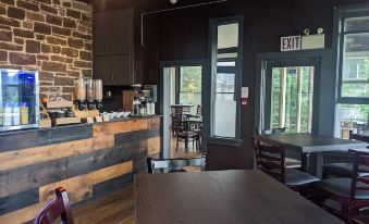 a modern cafe with wooden tables and chairs , stone walls , and an exit sign above the counter at Inn at the Falls