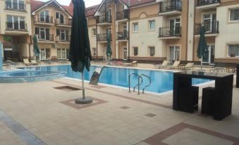 an outdoor swimming pool surrounded by apartment buildings , with a sun umbrella and lounge chairs nearby at Apartments Light