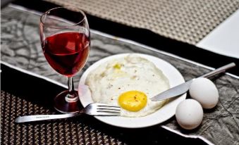 a plate with an egg on it , accompanied by a glass of red wine and a fork at The Opal