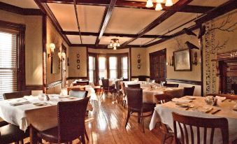 a large dining room with wooden floors , tables covered in white tablecloths and chairs arranged around them at The Inn