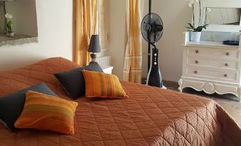 a cozy bedroom with a bed covered in a brown blanket and two orange pillows at Chambre d'hôtes - Mas de Louise