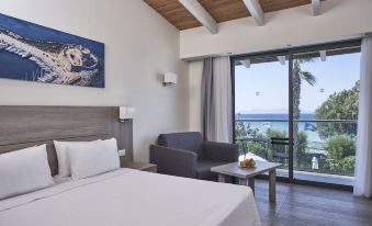 a hotel room with a large bed , a couch , and a window overlooking the ocean at Labranda Blue Bay Resort