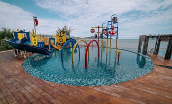 a large swimming pool with a colorful slide and playground equipment is surrounded by a wooden deck at Swiss-Belhotel Kuantan