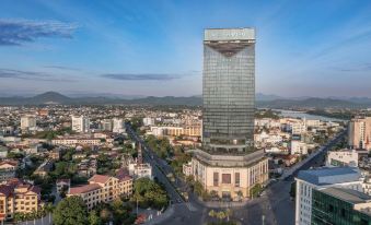 a cityscape with a large , modern building in the center surrounded by smaller buildings and trees at Melia Vinpearl Hue