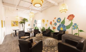 a cozy and colorful waiting area with black chairs and a large wall mural of flowers at Hotel du Nord