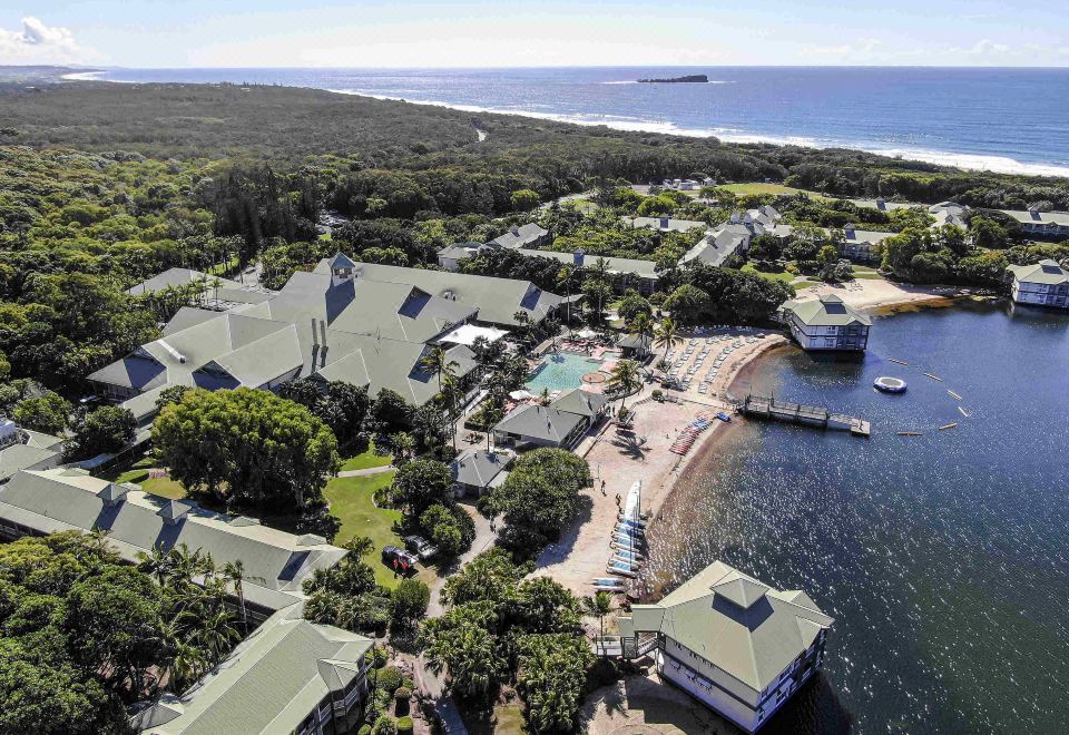 a bird 's eye view of a resort with buildings , a pool , and the ocean in the background at Novotel Sunshine Coast Resort