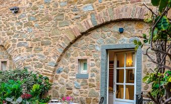 a small courtyard with a stone building , a table and chairs set up for outdoor dining at Monastero di Cortona Hotel & Spa