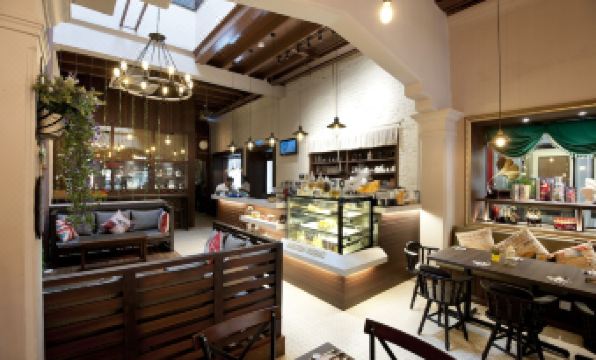 a modern cafe with wooden furniture , including tables and chairs , and a display case filled with beverages at Kimberley Hotel Georgetown