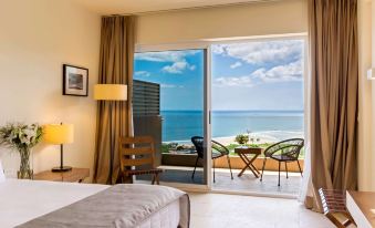 a bedroom with a large window overlooking the ocean , featuring a bed and chairs near the window at Wyndham Tamarindo