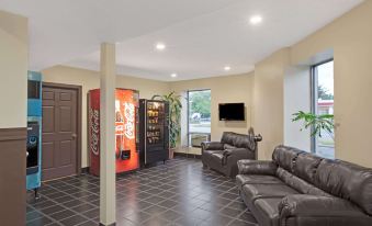 a living room with a couch , coffee table , and vending machine , as well as a tv on the wall at Knights Inn Pine Brook