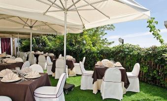 a well - arranged outdoor dining area with white and brown tablecloths , umbrellas , and chairs under a clear blue sky at Leonardo's