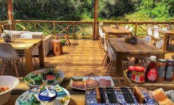 a wooden deck with dining tables , chairs , and a grill , as well as a variety of food items on the table at Forest Edge