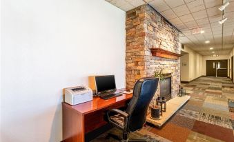 a computer desk with a laptop and printer is set up in front of a brick fireplace at Colony Motel Jamestown
