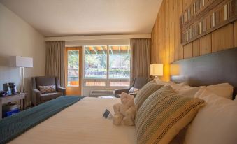 a cozy bedroom with a bed , pillows , and a teddy bear , along with a view of a swimming pool outside through the window at Fairmont Hot Springs Resort
