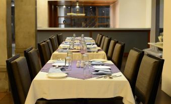 a long dining table set for a formal dinner , with multiple chairs arranged around it at Hotel Woodland
