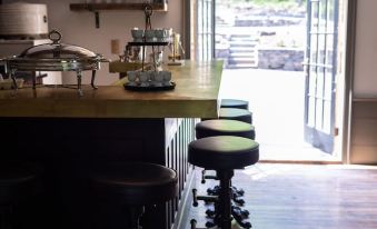 a room with a wooden table and several stools , featuring a coffee maker and cups at Stonehill's Farmhouse