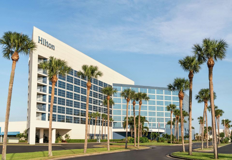 a large building with the hilton name on it , surrounded by palm trees and other greenery at Hilton Melbourne, FL