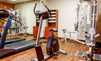 a well - equipped home gym with various exercise equipment , including a treadmill and stationary bike , on a wooden floor at Comfort Suites Gadsden Attalla