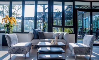 a modern living room with a large window , white couch , and coffee table , surrounded by comfortable seating and furniture at Suanpa Resort