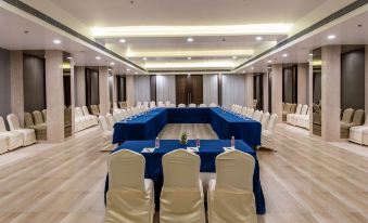 a large conference room with blue tables and white chairs , set up for an event at Regenta Central Jaipur