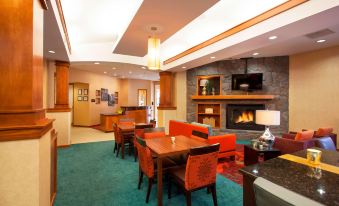 a modern hotel lobby with a fireplace , couches , dining tables , and chairs arranged for guests at Residence Inn Phoenix Goodyear