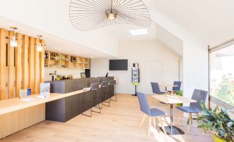 a modern kitchen and dining area with a wooden floor , blue chairs , and a large fan above the counter at Best Western Armor Park Dinan