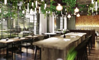 a modern restaurant with wooden tables and chairs , green plants hanging from the ceiling , and hanging lights at Mercure HAN Sur Lesse