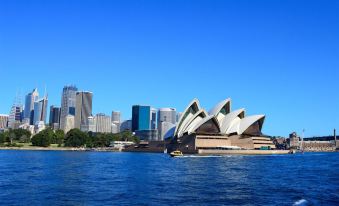 the sydney opera house , a large white building with multiple domes , is situated on a waterfront with skyscrapers in the background at Westside Motor Inn