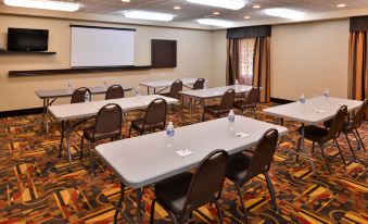 a conference room with multiple tables and chairs , water bottles , and a projector screen , set up for a meeting or presentation at Wingate by Wyndham Steubenville