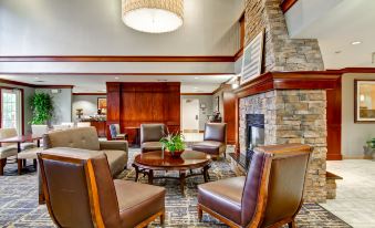 a cozy living room with a fireplace and several chairs arranged around it , creating a warm and inviting atmosphere at Homewood Suites by Hilton Stratford