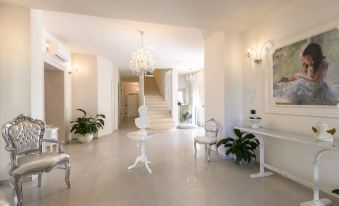 a white room with a chandelier , a table , chairs , and potted plants on the floor at Hotel San Giovanni