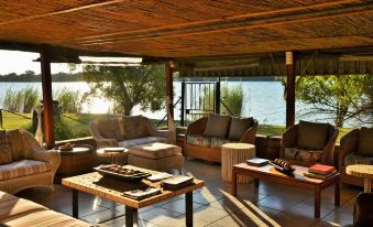 a modern living room with wooden furniture , including a couch , chairs , and a coffee table at River View Lodge