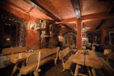 a cozy restaurant with wooden tables and chairs , a brick wall , and shelves filled with wine bottles at Troll