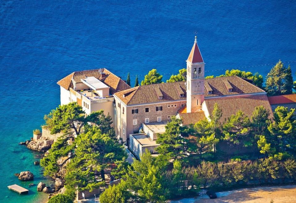 an aerial view of a large , multi - level building surrounded by trees and the ocean in the background at Bluesun Hotel Elaphusa