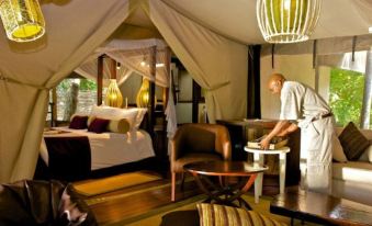 a man in a room with a canopy bed , using a laptop to interact with the occupants at Mara Intrepids Tented Camp