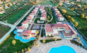 a bird 's eye view of a resort with a large pool and multiple buildings surrounded by greenery at Almyros Beach