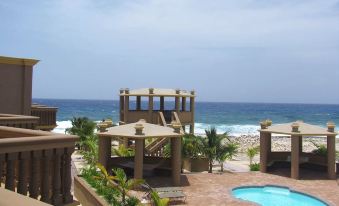 a beautiful beach resort with a swimming pool , umbrellas , and tropical plants , overlooking the ocean at Kings Point