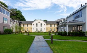 a large white building surrounded by a well - maintained green lawn and trees , with a pathway leading up to it at Briar Barn Inn