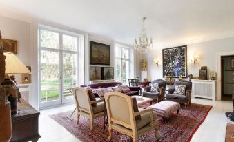 a spacious living room with a large flat - screen tv mounted on the wall , surrounded by various pieces of furniture such as chairs , a couch at B&B Harlington Manor